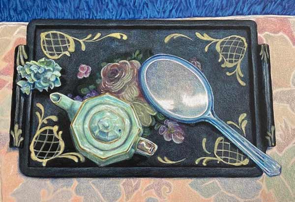 Black laquer tray with celedon teapot and flowers and blue lucite mirror on a pale floral place mat.